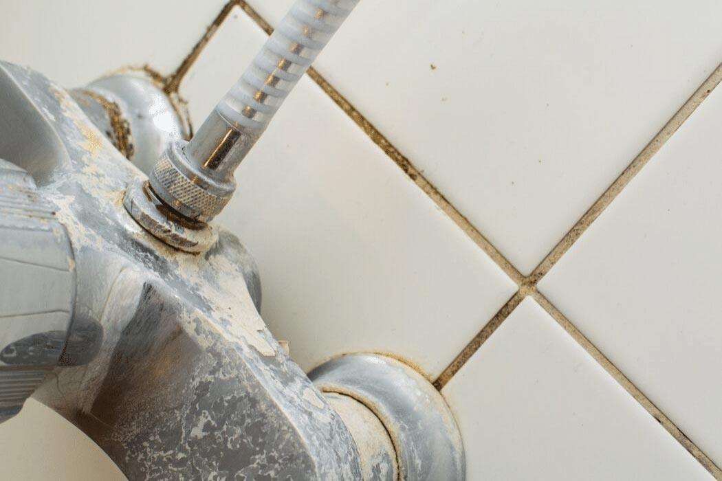 Close-up of a faucet showing mineral buildup and hard water stains on tile, highlighting common issues related to hard water in Texas homes.