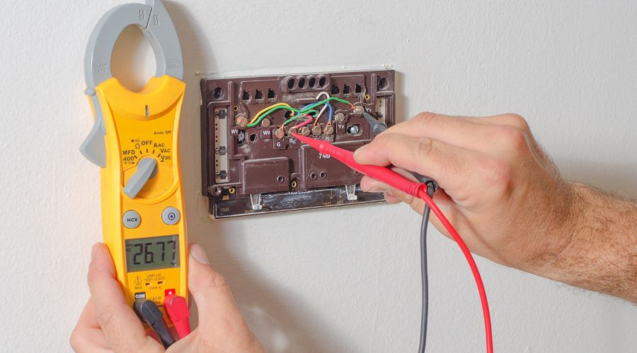 Electrical panel and multimeter displaying AC voltage 267.7 for plumbing and HVAC services in Kerrville, TX.