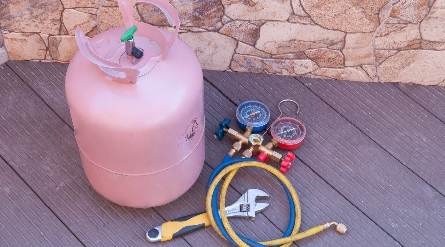 Refrigerant tank with pressure gauges and tools for HVAC maintenance, illustrating refrigerant issues and air conditioning service.