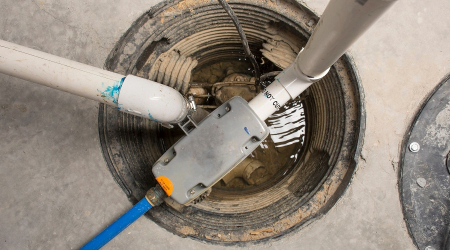 Sump pump system installed in a sump pump basin, featuring discharge pipes and water accumulation, illustrating plumbing solutions for basement flooding prevention.